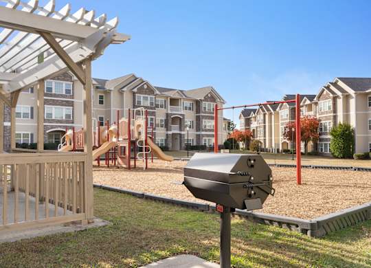 A playground with a slide and a swing set in front of apartment buildings. at Stone Gate Apartments, Spring Lake, North Carolina