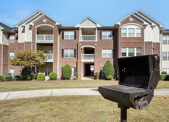 A bench with a laptop on it is in front of a building. at Village on the Lake Apartments, Apartments, Spring Lake, NC