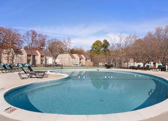A large outdoor swimming pool surrounded by lounge chairs and trees at Lakes Edge Apartments, Apartments, Greensboro, NC