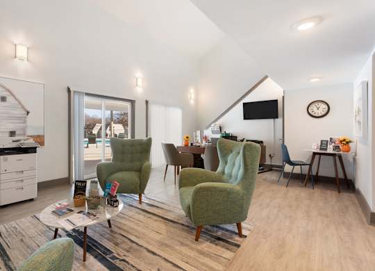A living room with a green chair and a white sofa at Lakes Edge Apartments, Greensboro, North Carolina
