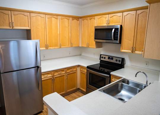 A kitchen with wooden cabinets and a stainless steel refrigerator.