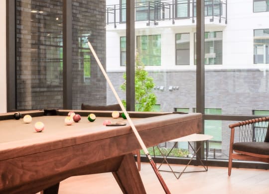 a pool table in a room with a chair and a window