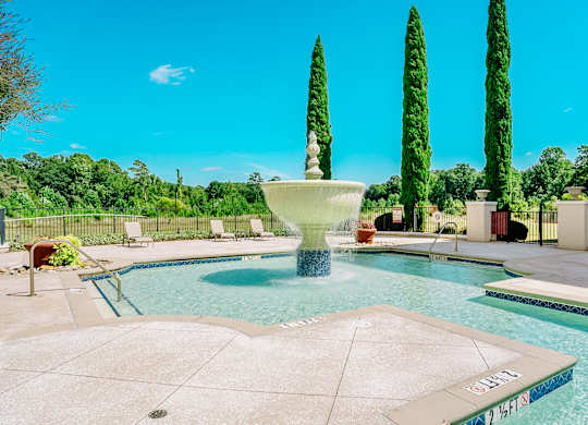 A pool with a fountain in the middle of it at The Villagio Apartments, Fayetteville, NC, 28303