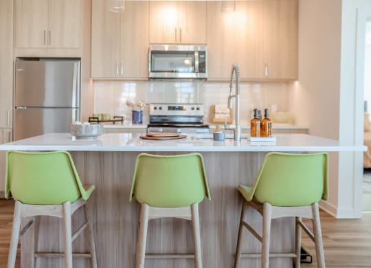 a kitchen with green chairs in front of a counter top