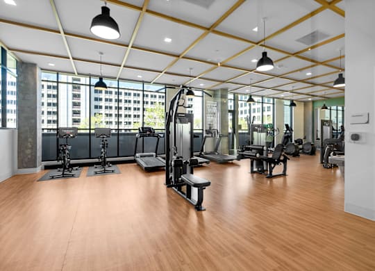 A gym with a variety of equipment and a view of a city skyline.