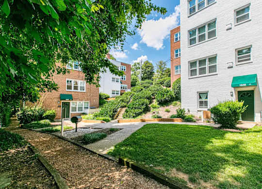 A white building with a green awning sits next to a grassy area. at Park Georgetown Apartments, Arlington, VA 22209