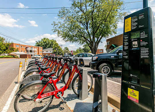 A row of red bikes are parked next to a bike rental station. at Park Georgetown Apartments, Arlington, VA