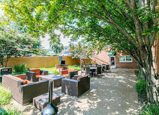 A patio with a table and chairs surrounded by trees. at Park Georgetown Apartments, Arlington, Virginia