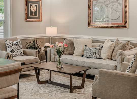 A living room with a grey couch, a coffee table, and a painting on the wall.