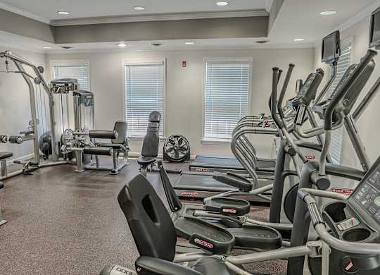 A gym with a variety of equipment including treadmills, weights, and exercise machines.