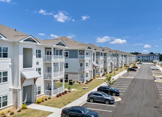 A row of houses with cars parked in front.
