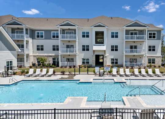 A large apartment complex with a pool in front.
