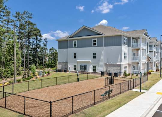 A large grey building with a fenced in yard in front.
