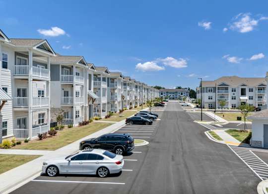 A row of white houses with cars parked in front.