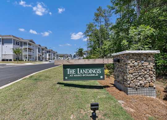 A sign for The Landings at Hard Scrabble is in front of a stone wall.