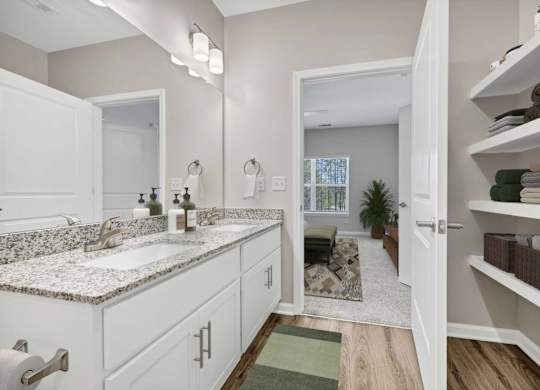 A bathroom with a marble countertop and white cabinets.