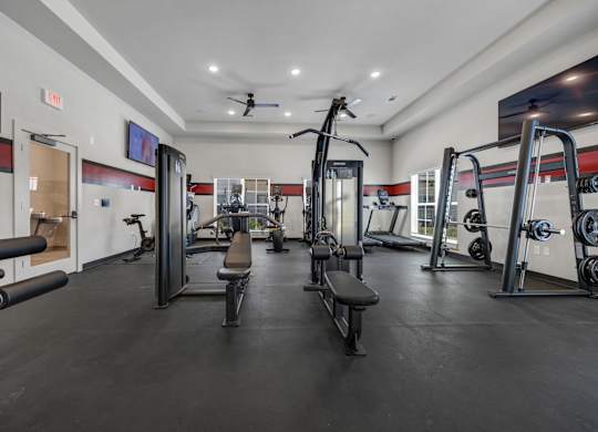 A gym with a variety of equipment including a squat rack, bench, and weights.