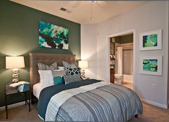 A bedroom with a bed, nightstand, and two lamps. at Kensington Place Apartments, Woodbridge, VA, 22191