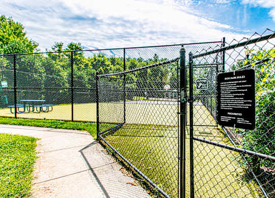 A sign on a fence indicates that dogs are not allowed in the park. at Barrington Park Apartments, Manassas, VA