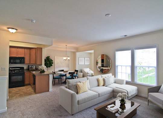 A well-lit, spacious living room with a kitchen area in the background. at Barrington Park Apartments, Manassas, Virginia