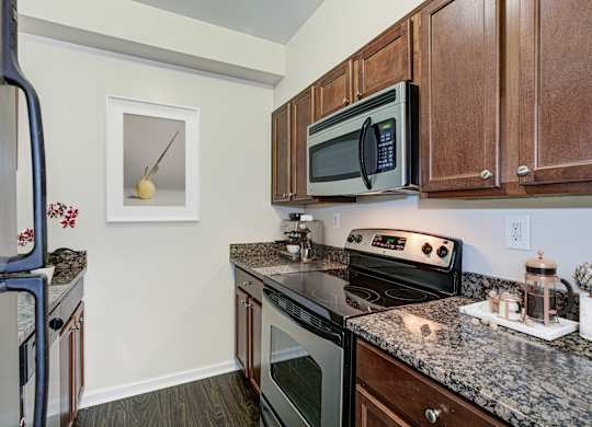 A kitchen with a black microwave above a stove. at Columbia Uptown Apartments, Washington, DC