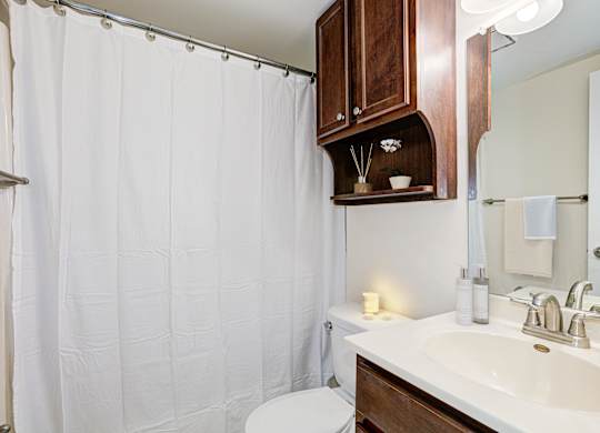 A white sink in a bathroom with a white shower curtain. at Columbia Uptown Apartments, Washington, Washington DC