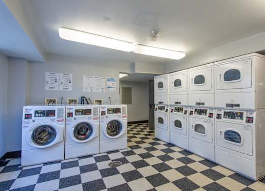 A row of washing machines are lined up in a laundromat. at Columbia Uptown Apartments, Washington