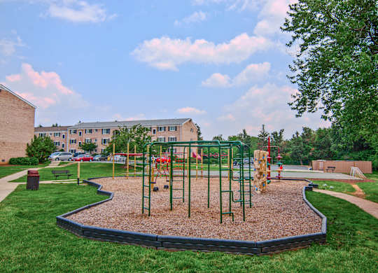 A playground with a red swing set and a green slide at Dulles Glen Apartments, Herndon