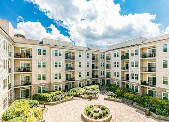 A courtyard surrounded by apartment buildings with a fountain in the middle. at Kensington Place Apartments, Woodbridge, Virginia