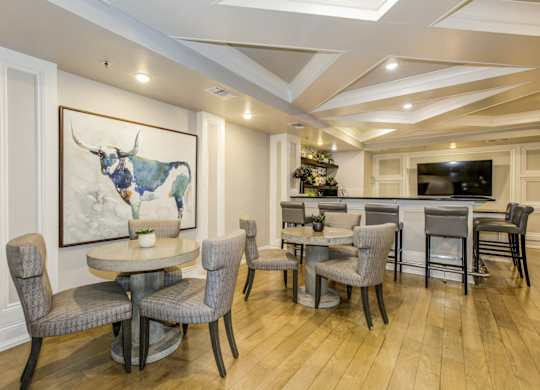 A dining room with a table and chairs and a painting of a bull on the wall. at Kensington Place Apartments, Woodbridge, 22191