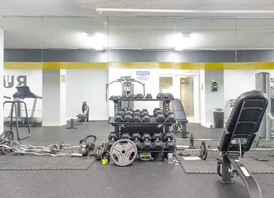 A gym with a variety of equipment including weights and a leg press machine.
