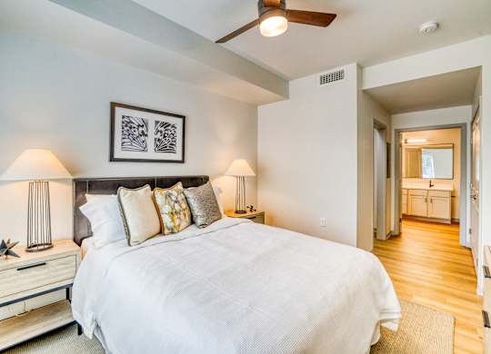 A bedroom with a large bed and a ceiling fan.
