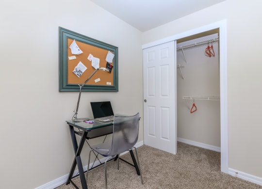 a small desk with a laptop and a lamp in the corner of a room with a closet