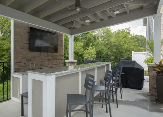 a bar with chairs and a television on a patio