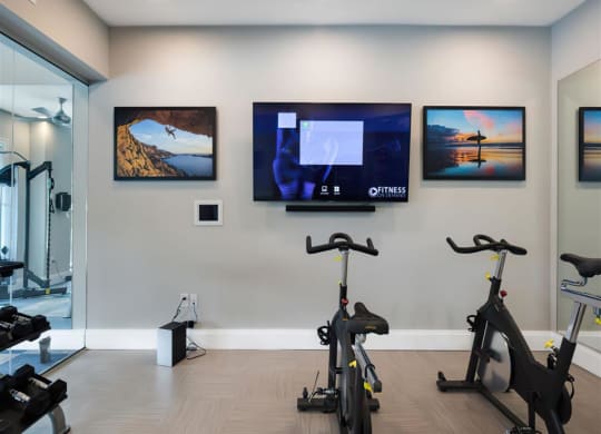 a home gym with exercise bikes and televisions on the wall