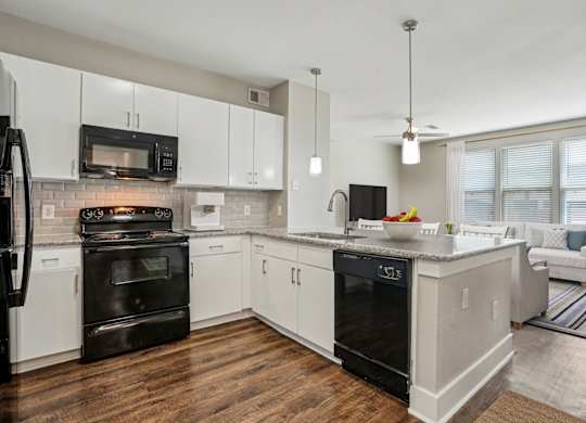 A modern kitchen with white cabinets and black appliances.