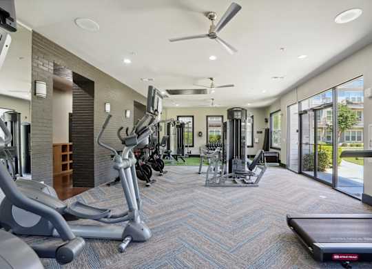 Bright fitness center with cardio equipment and large windows at Highline Urban Lofts Apartments, Cypress, Texas