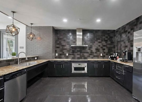 A modern kitchen with black cabinets and a stainless steel refrigerator.