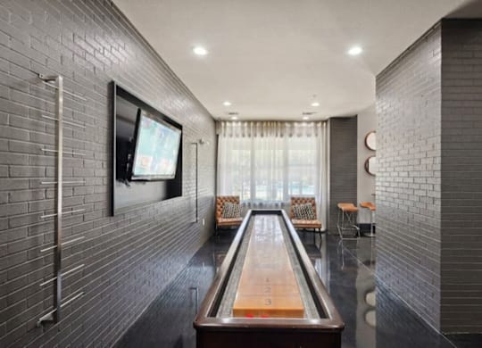 A room with a shiny wooden table in the middle and a television on the wall.