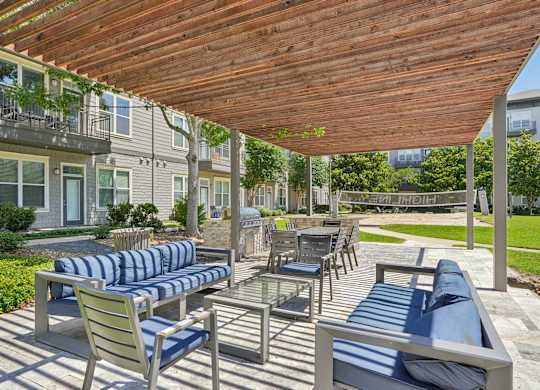 Covered outdoor lounge with striped seating and grilling station at Highline Urban Lofts Apartments, Cypress, TX