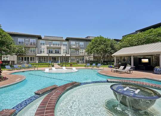 A large swimming pool with a waterfall and a fountain in the middle.
