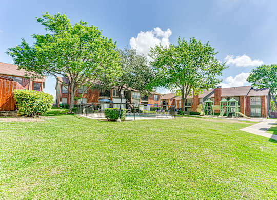 A grassy area in front of a row of houses at Bardin Oaks Apartments, Arlington, Texas