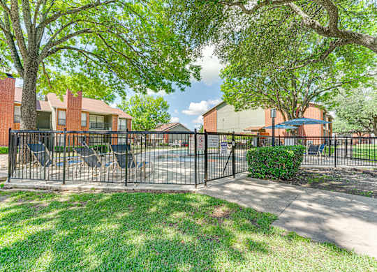 A black metal fence surrounds a green lawn at Bardin Oaks Apartments, Arlington