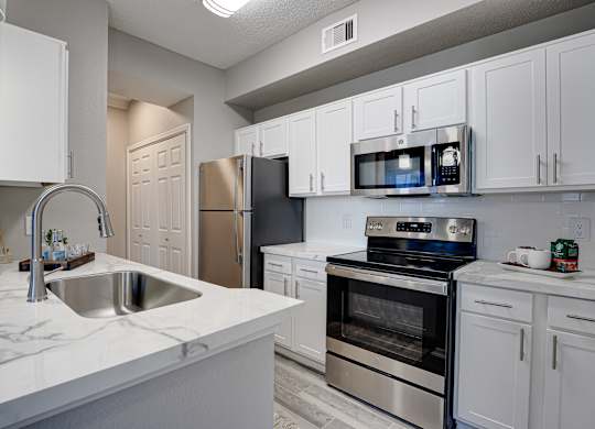 Modern kitchen with white cabinets and marble countertops at Carmel Creekside Apartments, Fort Worth, 76137