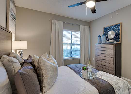 Bedroom with neutral decor and ceiling fan at Carmel Creekside Apartments, Texas