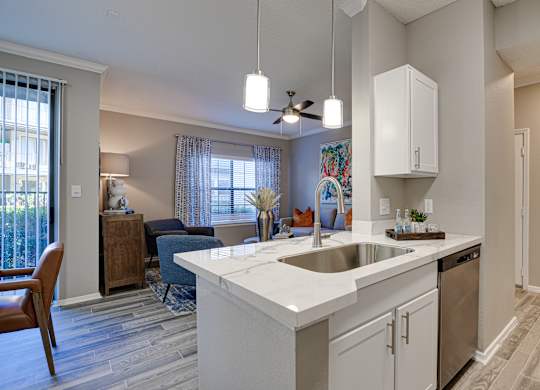 Kitchen island with stainless sink and pendant lights at Carmel Creekside Apartments, Fort Worth, 76137