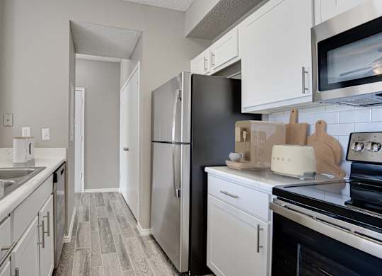 Galley kitchen with stainless steel appliances and marble countertops at Carmel Creekside Apartments, Fort Worth, TX