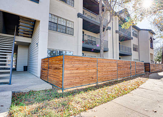 Apartment building exterior with wood privacy fence at Carmel Creekside Apartments, Texas, 76137