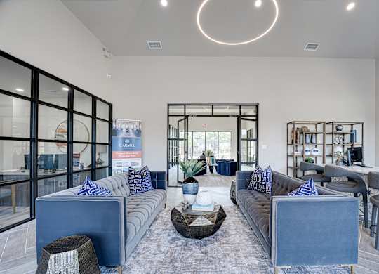 Clubhouse lounge with blue sofas and decorative shelving at Carmel Creekside Apartments, Texas