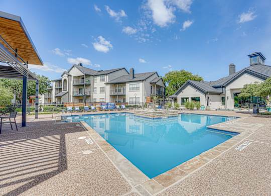 Resort style pool with lounge chairs and clubhouse at Carmel Creekside Apartments, Fort Worth